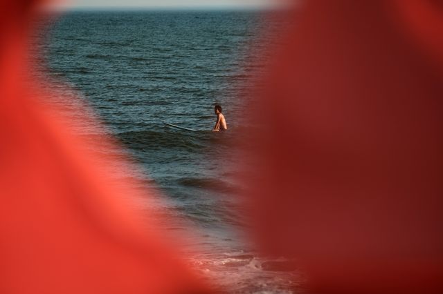 A surfer sits in the water on a warm evening at Rockaway Beach on July 19th, 2022.